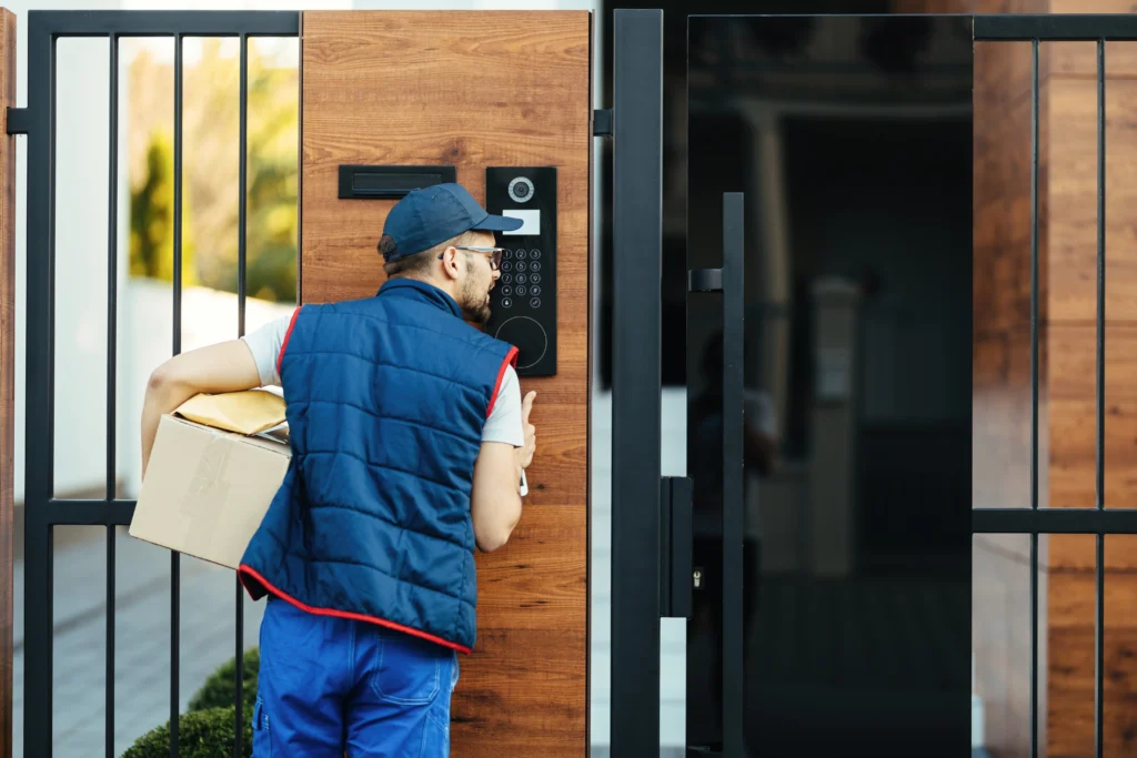 back view deliverer ringing intercom gate customer s house while delivering packages
